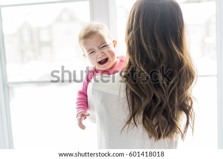 A newborn baby in the hand of his mother at the window
