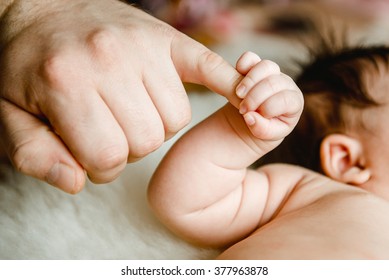 Newborn Baby Hand Holding Dad's Finger