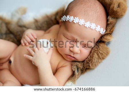 Newborn baby in the hat sleeping with a toy