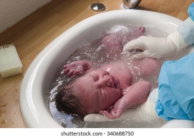 A Newborn Baby Is Having Her First Bath