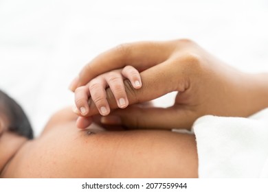 Newborn Baby Holding Mother’s Finder While Sleeping On White Bed. Mother Takes Care And Comforting For Her Baby