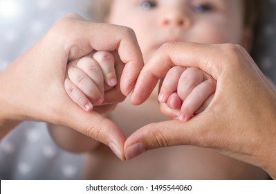 Newborn baby holding mother hands in heart shape , closeup baby's hand in mother's finger