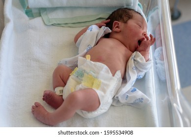 newborn baby in a hospital crib with a baby blanket 