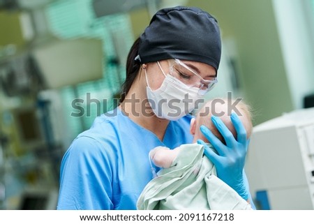 Newborn baby in hospital at neonatal resuscitation center with nurse