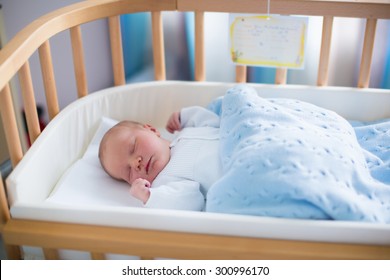 Newborn Baby In Hospital Room. New Born Child In Wooden Co-sleeper Crib. Infant Sleeping In Bedside Bassinet. Safe Co-sleeping In A Bed Side Cot. Little Boy Taking A Nap Under Knitted Blanket.