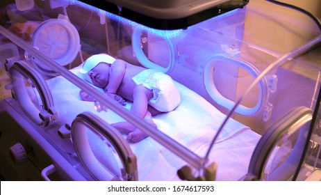Newborn baby in an incubator exposed to UV rays. A child with neonatal jaundice. A newborn baby in the hospital, right after birth, the first days of a child's life, illness and treatment.