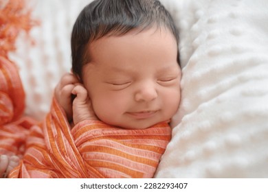 Newborn baby infant with dark hair smiling lying on side sleeping. Cute little Middle eastern child on blanket. Tranquil scene close up - Powered by Shutterstock