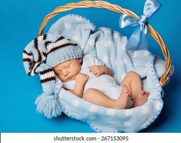 Newborn Baby Inside Basket, New Born Kid Dream In Woolen Hat, Little Child Boy Sleeping Over Blue Background