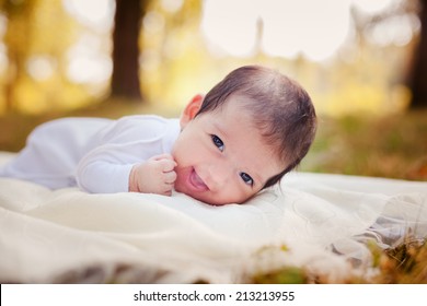 Newborn baby laying on the grass in the autumn park