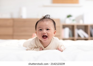 Newborn baby laying on stomach developing neck control .tummy time for strengthen baby neck and shoulder muscles.Cute infant lying crawling on white bed happiness and fun.Tummy Time Concept
