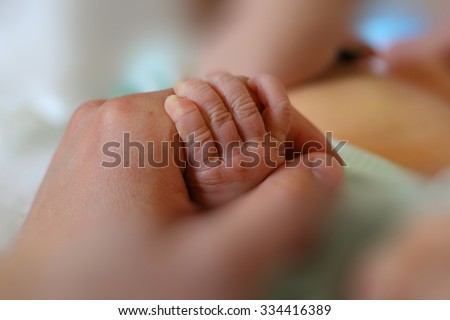 Newborn baby little hand hold by adult man hand of his father