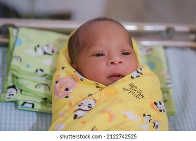 Newborn Baby Looks Comfortable Wearing A Yellow Baby Blanket.