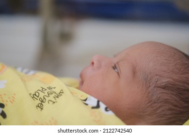 Newborn Baby Looks Comfortable Wearing A Yellow Baby Blanket.