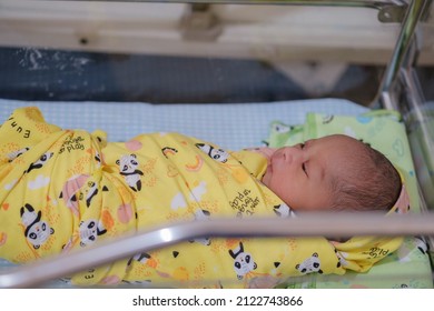 Newborn Baby Looks Comfortable Wearing A Yellow Baby Blanket.