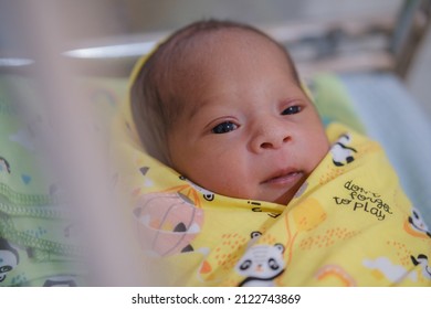 Newborn Baby Looks Comfortable Wearing A Yellow Baby Blanket.