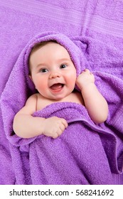 Newborn Baby Lying Down And Smiling In A Purple Towel