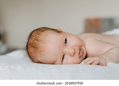 Newborn Baby Making Funny Face, Smiling, Lying On Bed.