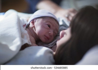 A Newborn Baby Rest On His Mothers Chest And Stares Into Her Eyes For The First Time.