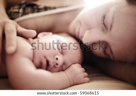 Newborn baby sleeping with mother. Shallow DOF.