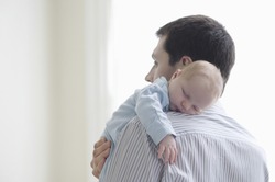 Newborn Baby Sleeping On Father's Shoulder At Home