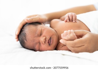 Newborn Baby Sleeping On White Bed While Mother’s Hands Takes Care Carefully. Family, Love And New Life Concept