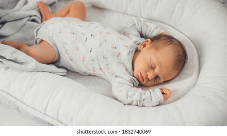 Newborn baby sleeping in safe in her bed on a white blanket at home