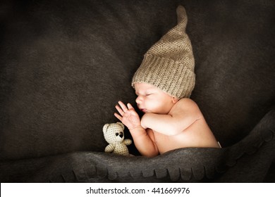 newborn baby sleeping  with a toy next to the  knitted teddy bear


