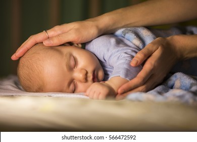 Newborn baby sleeps with caring touch of mother's hands, care concept - Shutterstock ID 566472592