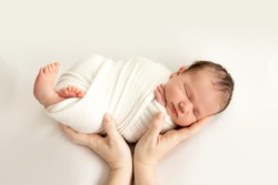 A Newborn Baby Sleeps Sweetly In His Mother's Arms On A White Background, Swaddling The Baby, A Place For Text.