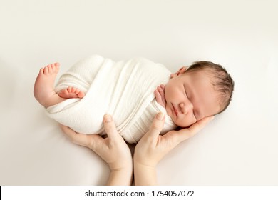 a newborn baby sleeps sweetly in his mother's arms on a white background, swaddling the baby, a place for text. - Shutterstock ID 1754057072