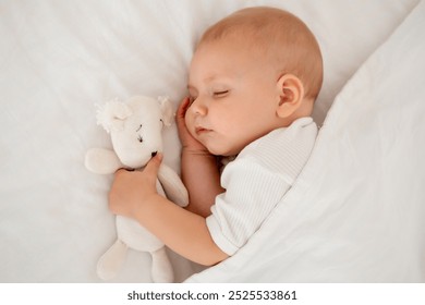 a newborn baby sleeps sweetly holding a toy in his hands, a place for text, a baby sleeps on a white bed under a blanket with a pen under his cheek, a healthy baby's sleep. - Powered by Shutterstock