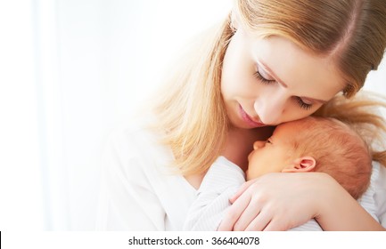 Newborn Baby In A Tender Embrace Of Mother At The Window