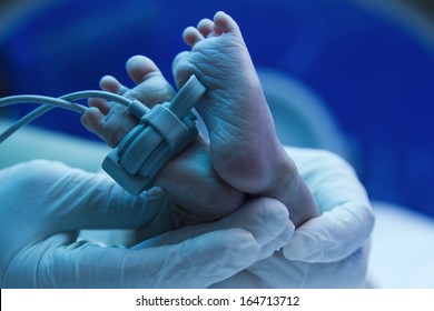 Newborn Baby Under Ultraviolet Lamp In The Incubator,Doctor's Hand Care For A Sick New Born  In The Pediatric ICU