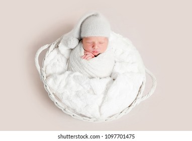 Newborn baby in white wrap laying on basket - Powered by Shutterstock