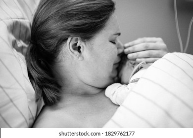 Newborn Baby Wrapped In Blankets After Birth. Mother Looking For The First Time On New Born Daughter. Newborn Child Seconds And Minutes After Birth. Happy Mum Crying