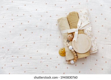 Neuer Hintergrund. Babymuslin mit Bogen und Bib. Leere Holzkarte. Geschenk für ein Neugeborenes