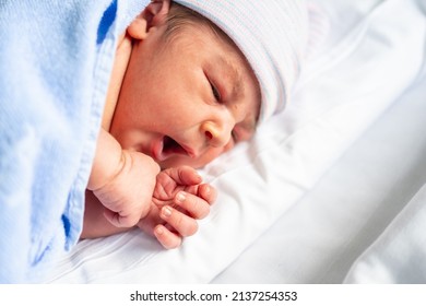 Newborn boy in the hospital, first day of life, yawning and looking to the right, copy space and paste