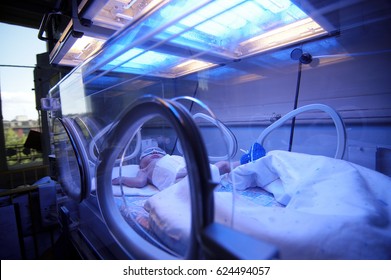 Newborn Child Baby Having A Treatment For Jaundice Under Ultraviolet Light In Incubator. A Neonatal Intensive Care Unit (NICU), Intensive Care Nursery (ICN) For Premature Newborn Infants