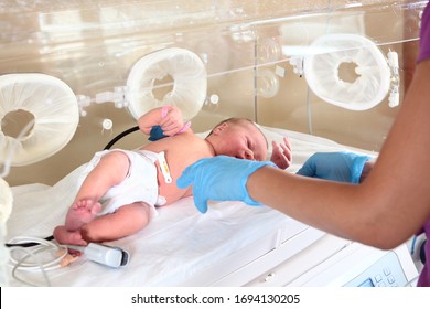 A newborn child in the pediatric Department. The doctor's hands are out of focus. The concept of saving human lives.