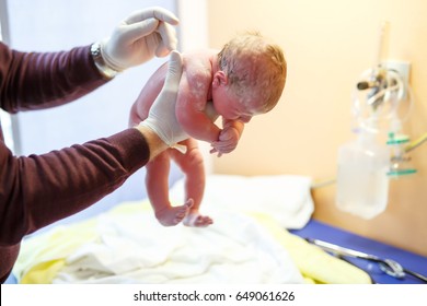 Newborn Child Seconds And Minutes After Birth. Doctor Hands With New Born Baby. Medical Check Up Of Health And Reflexes Of Child. New Life, Beginning, Healthcare.