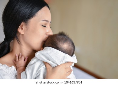 Newborn Concept. Mother And Child On A White Bed. Mom And Baby Boy Playing In Bedroom. Parent And Little Kid Relaxing At Home. Family Having Fun Together. Newborn Baby Is Fussing And Crying.