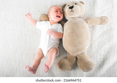 Newborn crying with bear toy close up. Baby care concept..