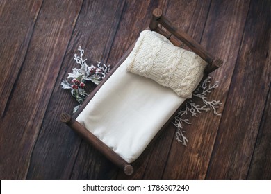 Newborn digital background - dark wooden bed with neutral gray  and white knitted pillow on wooden floor. Winter decor for newborn backdrop - white branches with red berries