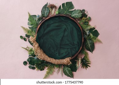 Newborn digital background - wooden bowl with pink faux fur on jute layer and pink backdrop and green leaves wreath. Tropical monstera plant wreath