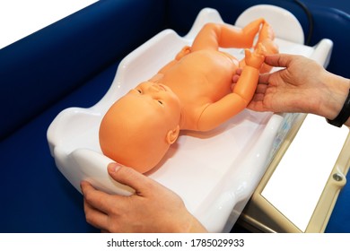 Newborn dummy on electronic scales. Practice of caring for a child of future parents on a plastic doll. Close-up