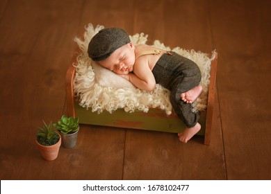 
A newborn in a fashionable suit sleeps in a crib. Photoshoot of a newborn. Stylish suit for the baby. Fashion kid. A newborn in a cap and hats. The child sleeps in the crib. Deep sleep. Autumn