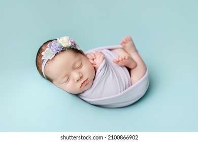 Newborn girl  on a blue background. Photoshoot for the newborn.  A portrait of a beautiful  
sleeping newborn baby girl