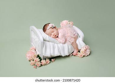 Newborn girl on a green background. Photoshoot for the newborn. A portrait of a beautiful sleeping newborn baby girl