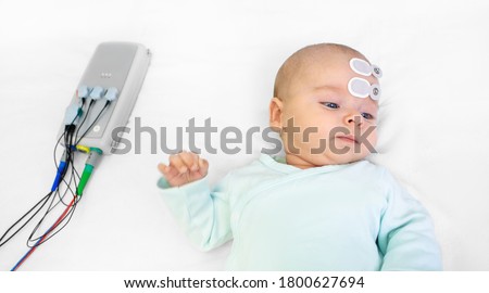 Newborn hearing screening and diagnosis at the hospital. Baby having hearing screening with special electrodes on his head and ear