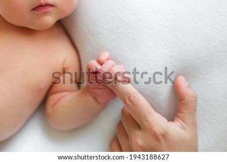 The newborn is holding a finger of mother on a white background. The newborn squeezes a finger. Family and home concept. Healthcare, pediatrics. Motherhood. Newborn and parent. Baby. Copy space